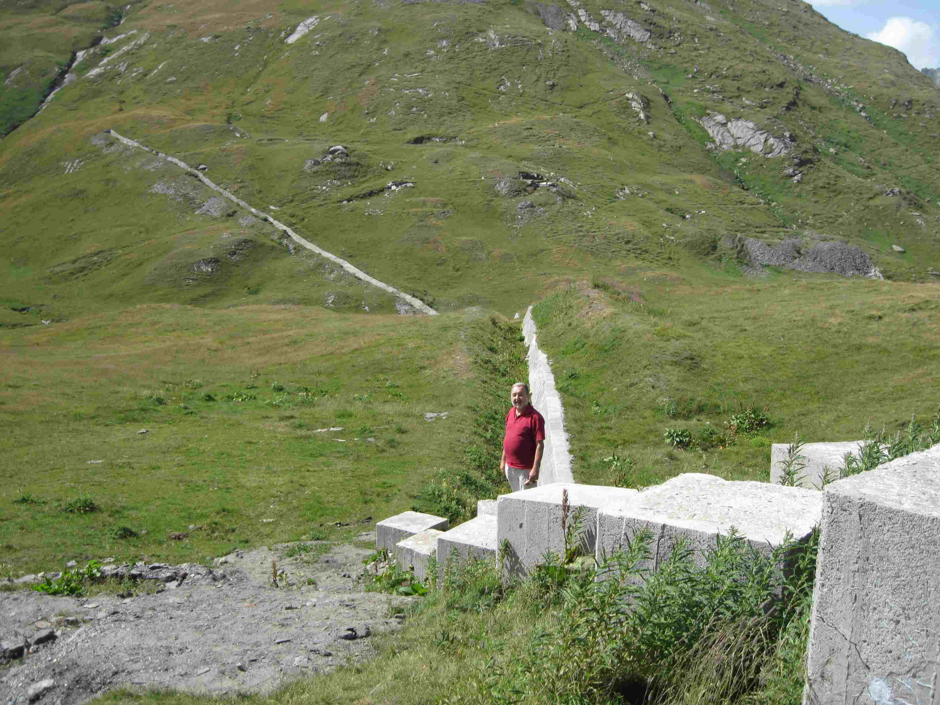 90 r questo è l’altro versante del Passo – visibile nella foto 03 di Tracer - (l’Italia è alle mie spalle, 100 metri indietro c’è la nuova linea di confine che taglia la strada) qualche centinaio di metri più avanti c’è la vecchia linea, dove il territorio italiano comprendeva l’Ospizio e la Chanousia (giardfino botanico delle erbe di montagna fondato dall’Abate Chanoux