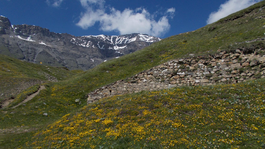 Muro di contenimento,sullo sfondo parzialmente coperta dalle nubi Cima Roncia