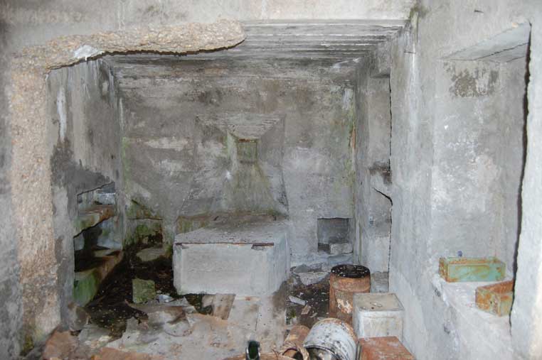 L'interno della casamatta con la feritoia murata,il basamento dell'arma e materiale vario sul pavimento